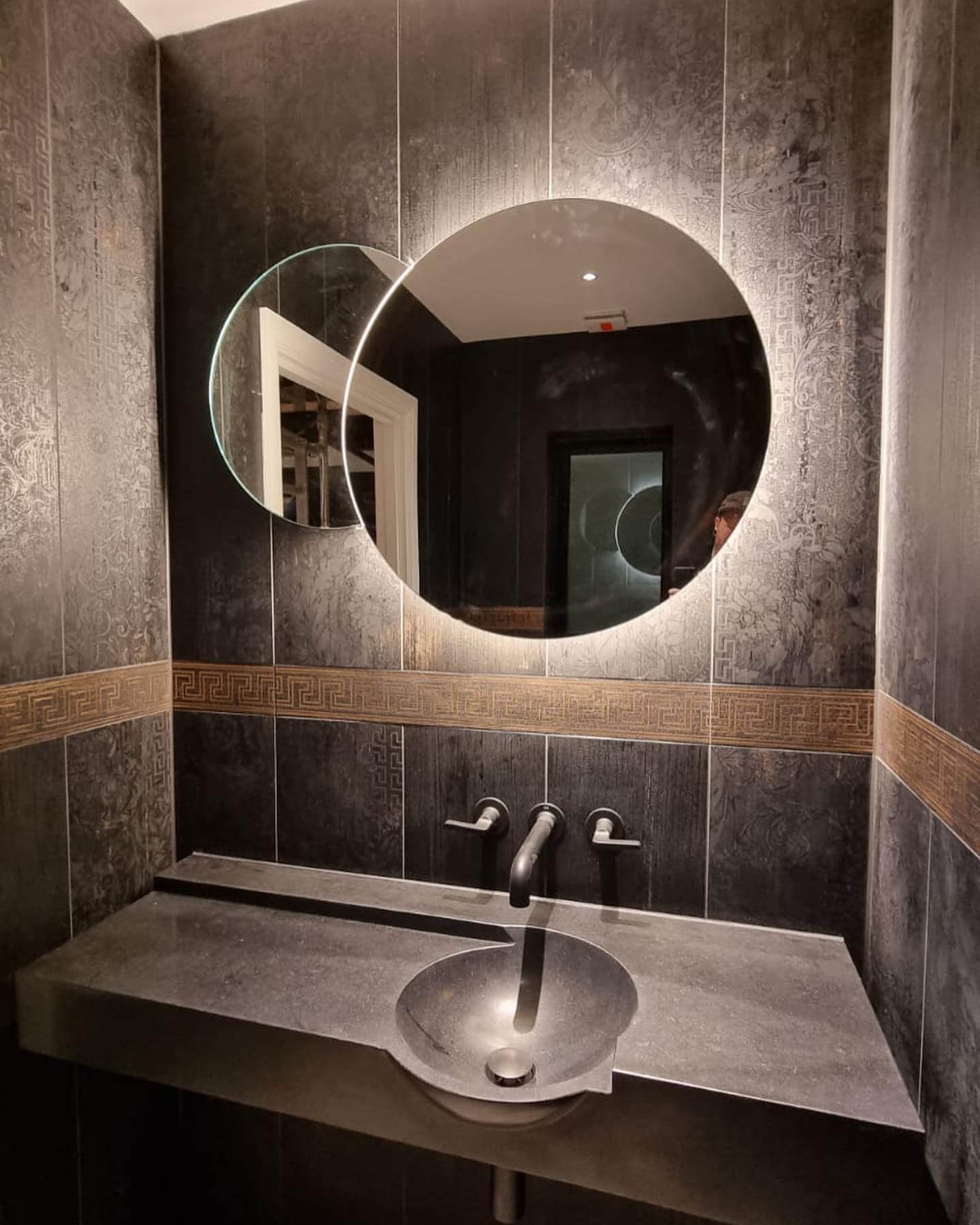 Bespoke bathroom with circular backlit mirror and stone basin
